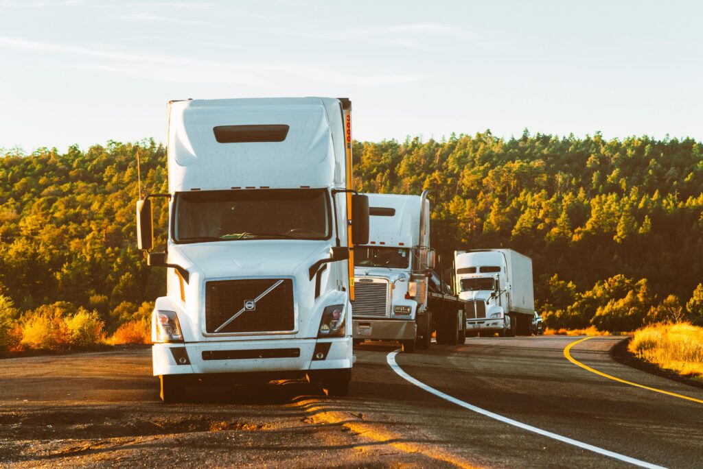 Three semi trucks driving on a highway through a forested landscape in Arizona. high pyaing niches